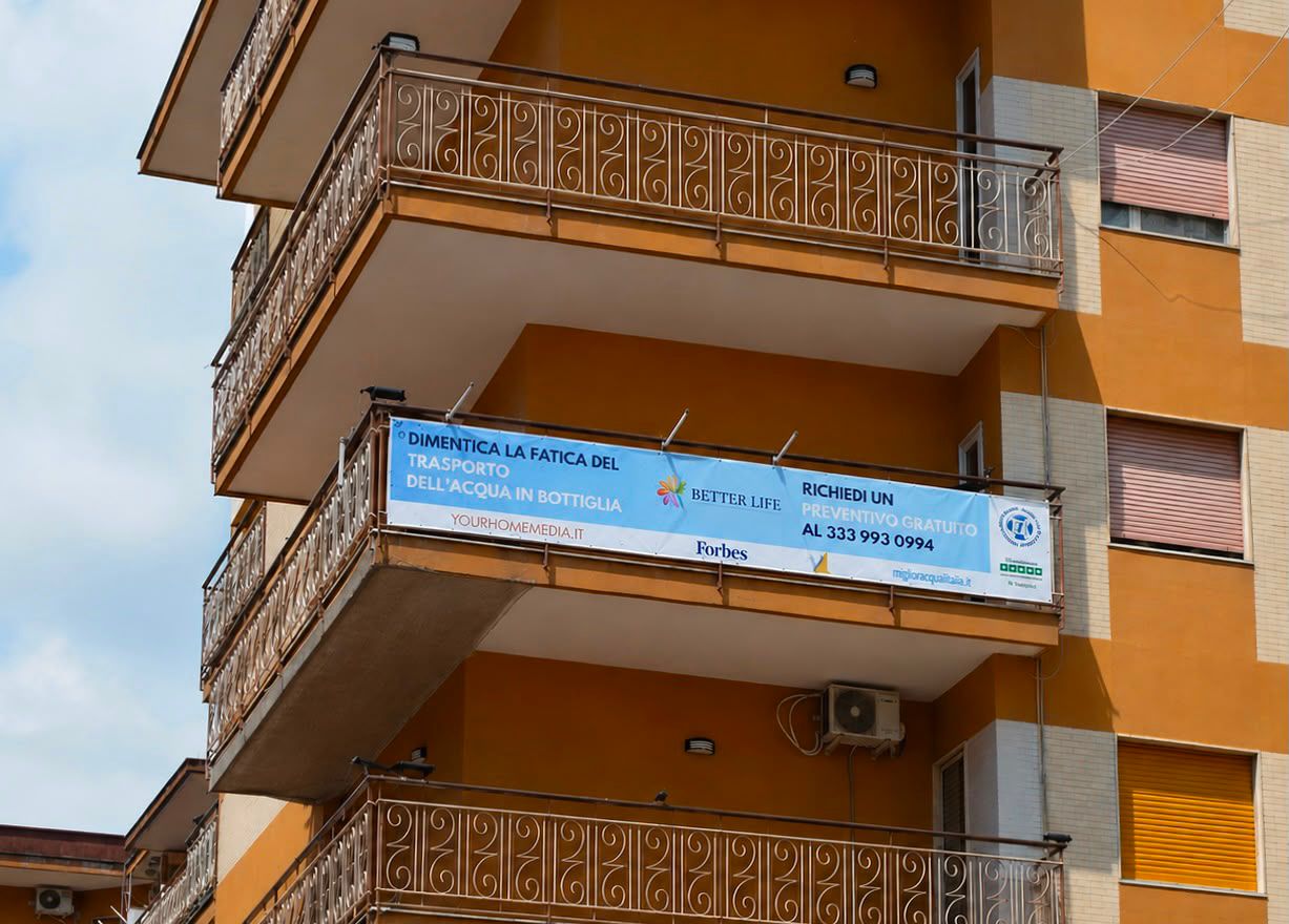 Balcone di un edificio arancione con un lungo banner pubblicitario